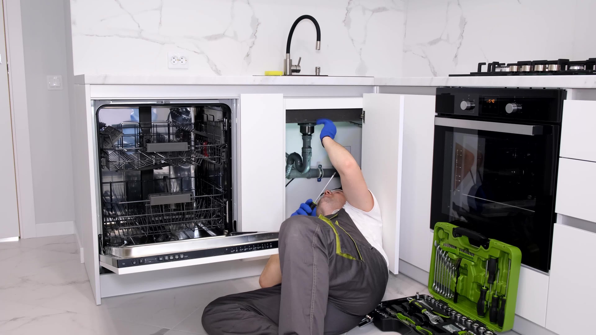 Top view of a plumber repairing a dishwasher. Calling a plumber to the house. A professional plumber