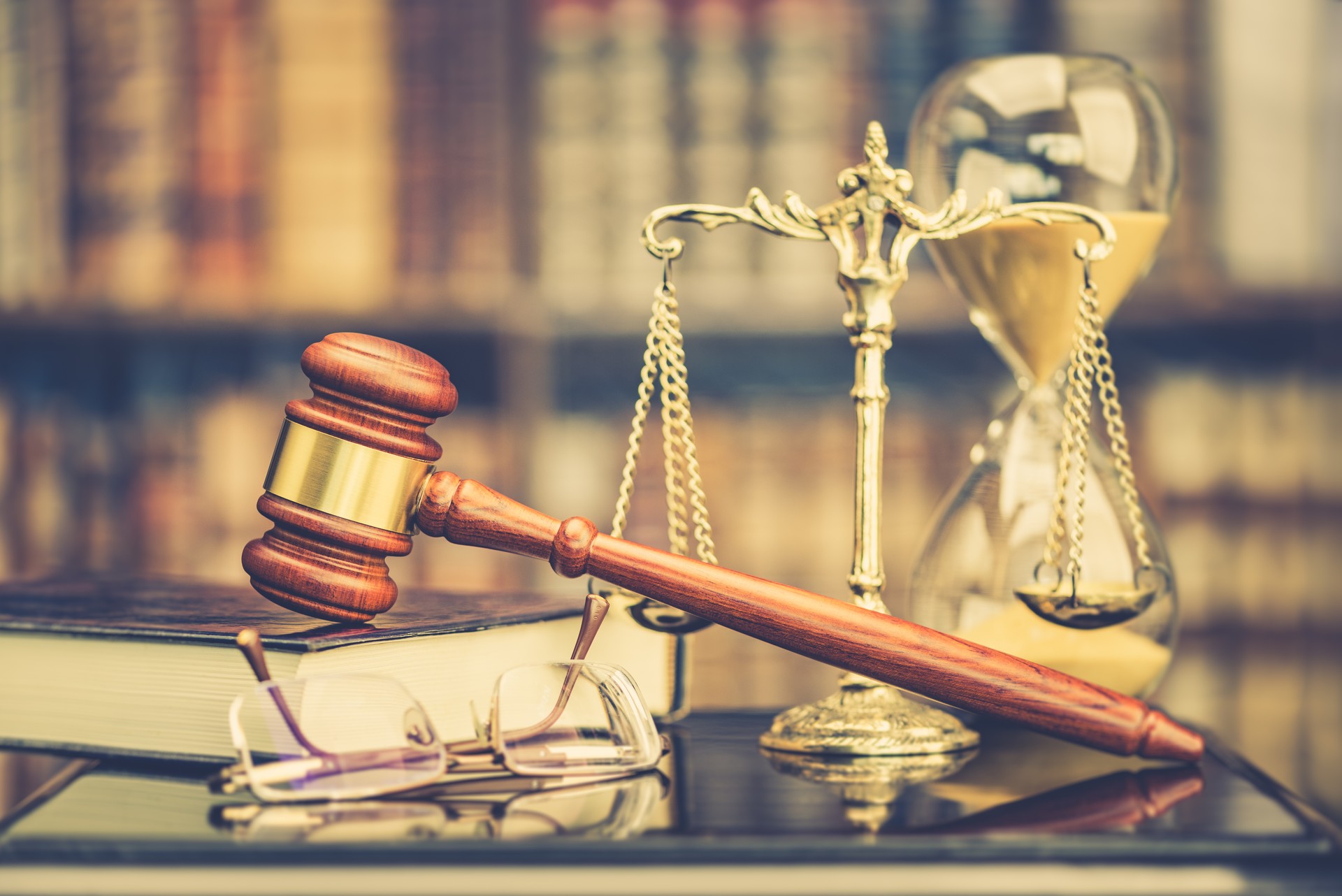 Legal office of lawyers, justice and law concept : Judge gavel or a hammer and a base used by a judge person on a desk in a courtroom with blurred weight scale of justice, bookshelf background behind.